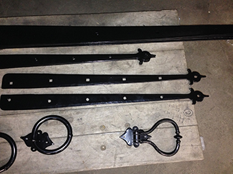 Forged black strap hinges and ring pulls on the workbench